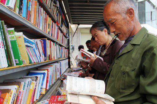 (130513) -- SUICHUAN, May 13, 2013 (Xinhua) -- People read books in front of the "moving library" in Suichuan County, east China\