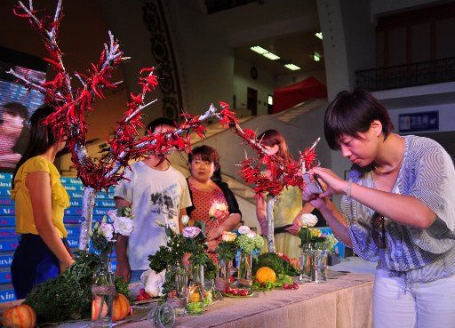(130819) -- BEIJING, Aug. 19, 2013 (Xinhua) -- A visitors takes a picture of vegetable-made decorations used for wedding feast at a summer wedding fair in Beijing Exhibition Center, Beijing, China, Aug. 18, 2013. The wedding fair, featuring ...