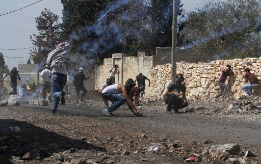 (130927) -- NABLUS, Sept. 27, 2013 (Xinhua) -- Palestinian protesters take cover from a gas tear shot by the Israeli soldiers during a protest against the expanding of Jewish settlements in Kufr Qadoom village near the West Bank city of Nablus on ...