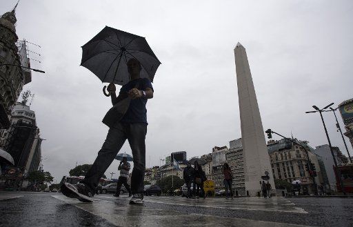 (140102) -- BUENOS AIRES, Jan. 2, 2014 (Xinhua) -- Residents walk in the rain in Buenos Aires, capital of Argentina, on Jan. 2, 2014. Storms landed in part of Argentina and have lowered the temperature here about 20 degrees Celsius. National Weather ...