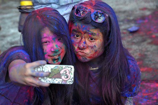 (140323) -- JAKARTA, March 23, 2014 (Xinhua) -- Girls take selfies with a cellphone during celebration of the Holi festival in Jakarta, Indonesia, March 23, 2014. The festival of Holi, a carnival of colors, is celebrated to mark the beginning of ...