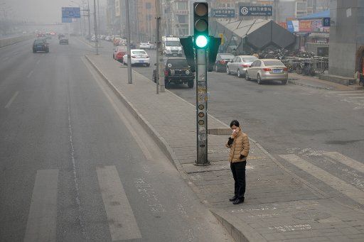 (140327) -- BEIJING, March 27, 2014 (Xinhua) -- A pedestrian wearing mask waits to cross a road in Beijing, capital of China, March 27, 2014. Beijing has maintained a yellow smog alert since Monday. A cold air can be expected at weekend, when most ...