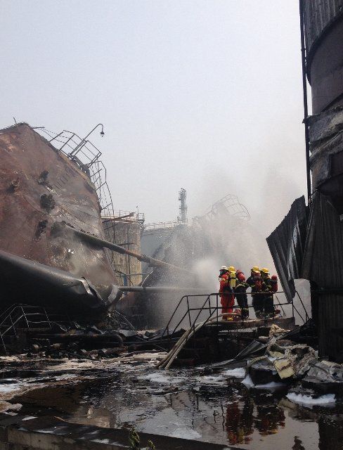 (140609) -- NANJING, June 9, 2014 (Xinhua) -- Photo taken with a mobile phone shows firemen putting out fire at the accident site after an explosion ripped through the refinery of Sinopec Yangzi Petrochemical Co. in Nanjing, capital of east China\