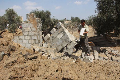 (140706) -- GAZA, July 6, 2014 (Xinhua) -- A Palestinian inspects a damaged chicken coop after an Israeli air strike in the southern Gaza Strip city of Khan Younis on July 6, 2014. Israeli warplanes hit targets belonging to militants in the Gaza ...