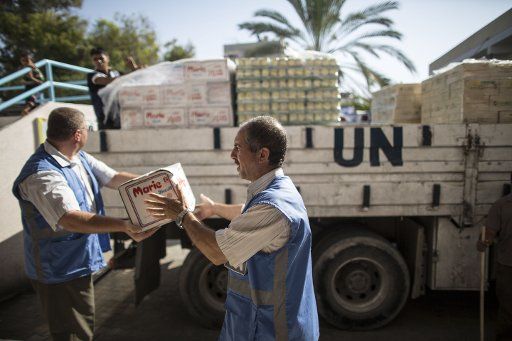 (140819) -- GAZA, Aug. 19, 2014 (Xinhua) -- Palestinian United Nations (UN) workers distribute supplies donated by the UN Relief and Works Agency for Palestine Refugees (UNRWA) for hundreds of displaced civilians, who take their shelter at one of ...