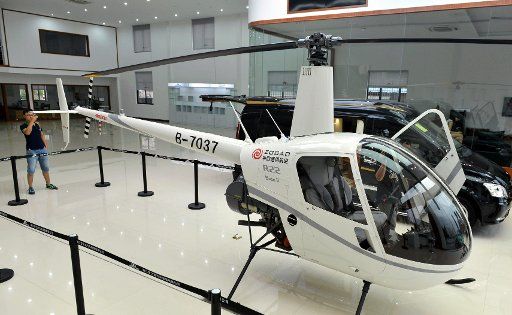 (140811) -- HANGZHOU, Aug. 11, 2014 (Xinhua) -- A man looks at a helicopter in the store of helicopter manufacturer ZOGAO in Hangzhou, capital of east China\