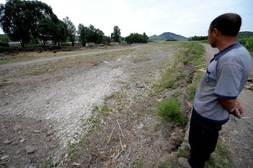 (140813) -- FUXIN, Aug. 13, 2014 (Xinhua) -- A villager stands beside a dried river channel in Qingshan Village of Fuxin Mongolian Autonomous County, northeast China\