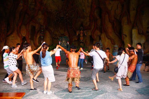 (140918) -- WUHU, Sept. 18, 2014 (Xinhua) -- Visitors play a dance of Wa ethnic group with employees at Wuhu Fangte "dream kingdom" theme park in Wuhu, east China\
