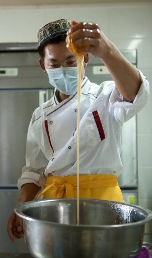 (140907) -- YINCHUAN, Sept. 7, 2014 (Xinhua) -- Zhou Xidong checks consistency of the syrup used for making moon cakes in his pastry shop Qingxinzhai in Yinchuan, capital of northwest China\