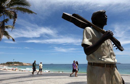(141209) -- RIO DE JANEIRO, Dec. 9, 2014 (Xinhua) -- People walk near a statue of Tom Jobim at the Ipanema beach in Rio de Janeiro, Brazil, on Dec. 8, 2014. According to local press, a statue of Brazilian songwriter Tom Jobim, author of the song "...
