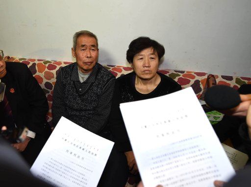(141215) -- BEIJING , Dec. 15, 2014 (Xinhua) -- Li Sanren (L) and Shang Aiyun, parents of Huugjilt who was executed in a controversial 1996 rape and murder case, receive legal document on retrial in Hohhot, capital of north China\