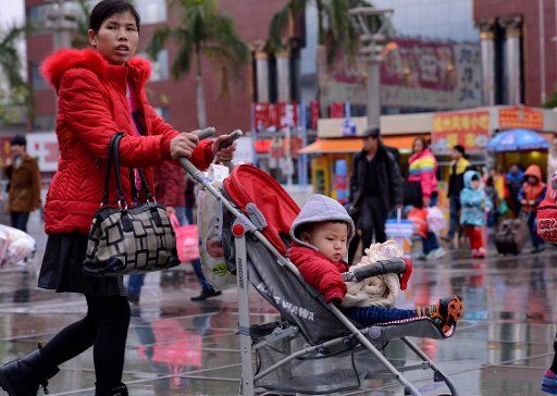 (150204) -- FUZHOU, Feb. 4, 2015 (Xinhua) -- A woman pushing a stroller with her child in it walks towards the waiting hall of the railway station of Fuzhou, capital of southeast China\