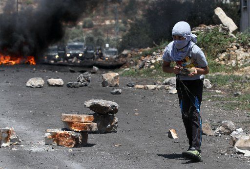 (150711) -- NABLUS, July 10, 2015 (Xinhua) -- A Palestinian protester throws stones at Israeli soldiers during a protest against the expanding of Jewish settlements in Kufr Qadoom village near the West Bank city of Nablus, on July. 10, 2015. (Xinhua\/...