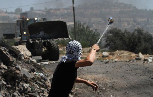 (150828) -- NABLUS, Aug. 28, 2015 (Xinhua) -- A Palestinian protester throws stones at Israeli soldiers during a protest against the expanding of Jewish settlements in Kufr Qadoom village near the West Bank city of Nablus, Aug. 28, 2015. (Xinhua\/...