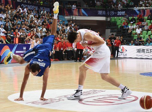 (150927) -- CHANGSHA, Sept. 27, 2015, (Xinhua) -- Zhou Peng (R) of China dodges as Rustam Murzagaliyev of Kazakhstan falls down during their FIBA Asia Championship second round Group F match in Changsha, capital of central China\