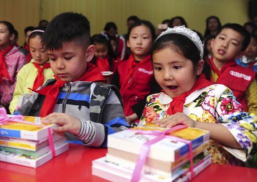 (160424) -- URUMQI, April 24, 2016 (Xinhua) -- Children hold books in an event to meet fiction writer Cao Wenxuan in Urumqi, capital of northwest China\