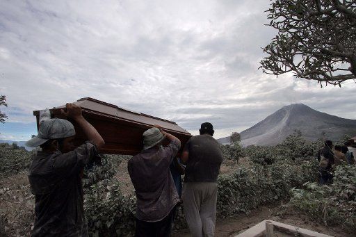 (160522) -- NORTH SUMATRA, May 22, 2016 (Xinhua) -- People carry a coffin to a mass grave during a funeral ceremony for victims in Mount Sinabung eruption at Sukandebi village in Karo, North Sumatra, Indonesia, May 22, 2016. The death toll from the ...