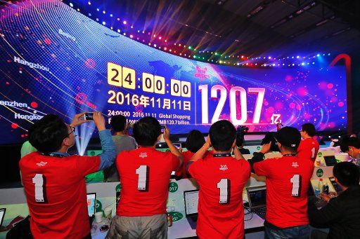 (161112) -- SHENZHEN, Nov. 12, 2016 (Xinhua) -- Staff members take photos of a giant screen displaying total gross merchandise volume (GMV) of Alibaba\