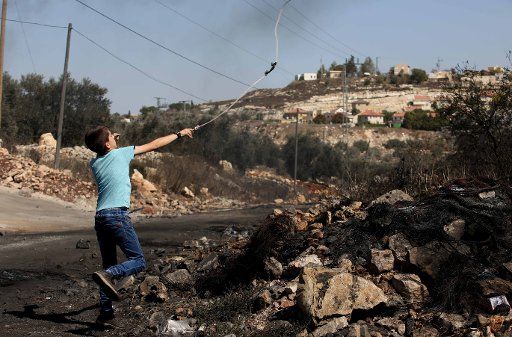 (161007) -- NABLUS, Oct. 7, 2016 (Xinhua) -- A Palestinian protester hurls stones at Israeli soldiers during clashes after a protest against the expanding of Jewish settlements in Kufr Qadoom village near the West Bank city of Nablus, on Oct. 7, ...