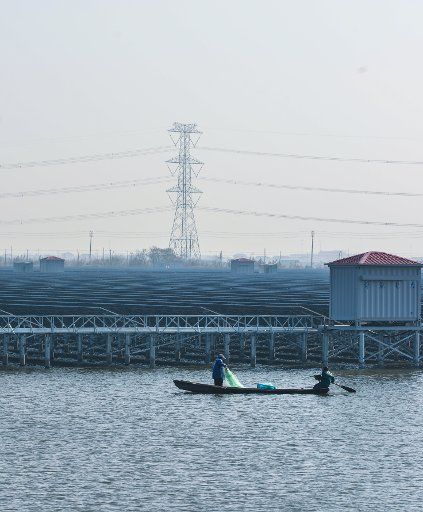 (161224) -- CIXI, Dec. 24, 2016 (Xinhua) -- Fishermen fish in an aquaculture farm building and sharing with a solar power project in Cixi City, east China\