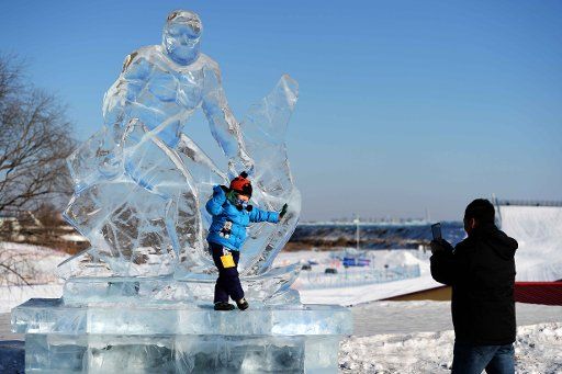 (170110) -- HARBIN, Jan. 10, 2017 (Xinhua) -- A parent takes photos of his kid in front of an ice sculpture at an activity center in Harbin, capital of northeast China\