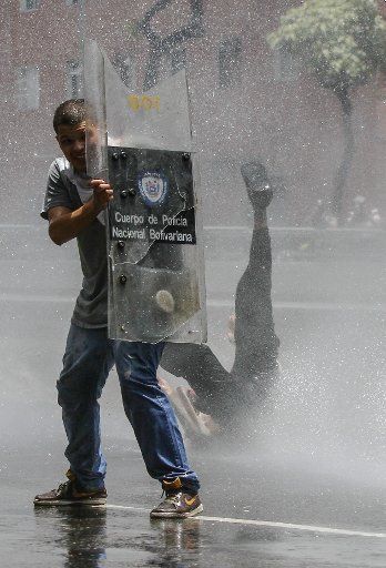(170405) -- CARACAS, April 5, 2017 (Xinhua) -- A man takes shelter during clashes with members of the Bolivarian National Police in Caracas, capital of Venezuela, on April 4, 2017. Supporters of Venezuela\