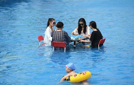 (170802) -- CHONGQING, Aug. 2, 2017 (Xinhua) -- People play mahjong in a swimming pool to cool off at a waterpark in Chongqing, southwest China, Aug. 2, 2017. A red alert for high temperatures was issued by Chongqing meteorological observatory on ...