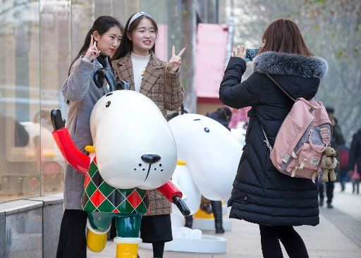 (180117) -- NANJING, Jan. 17, 2018 (Xinhua) -- People pose for a photo with the cartoon dog sculptures in Nanjing, east China\