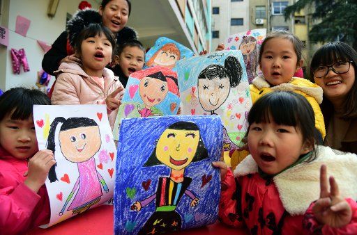 (180311) -- BEIJING, March 11, 2018 (Xinhua) -- Children show their drawings depicting their mothers during an activity ahead of the International Women\