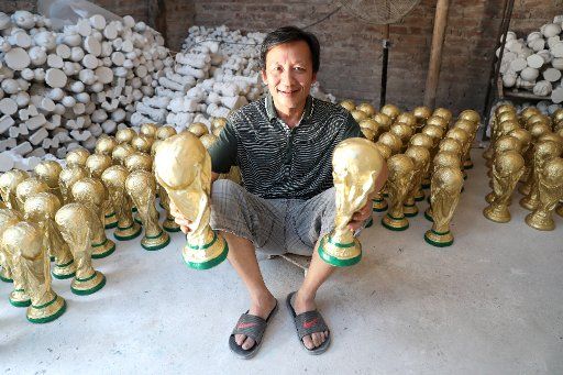 (180620) -- HANOI, June 20, 2018 (Xinhua) -- The owner of a pottery studio holds plaster World Cup trophy souvenirs in the Bat Trang ceramic village in Hanoi, capital of Vietnam, June 19, 2018. The Bat Trang ceramic village is renowned for its ceramic products of high quality. (Xinhua\/Wang Di) (gj)