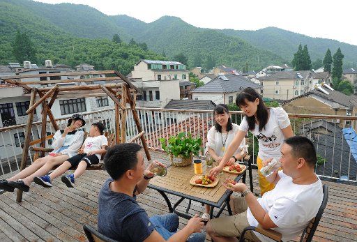 (180709) -- ANJI, July 9, 2018 (Xinhua) -- Hostess Li Qing (2nd R) offers fruit to guests at a family hostel in Yucun Village of Anji County, east China\