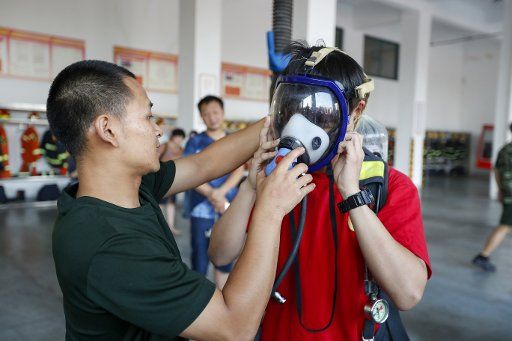 (180825) -- XIANGYANG, Aug. 25, 2018 (Xinhua) -- A student (R) from Xiangyang No. 5 Middle School learns to wear a respirator under the instruction of a fire fighter at a fire brigade of Xiangyang City, central China\
