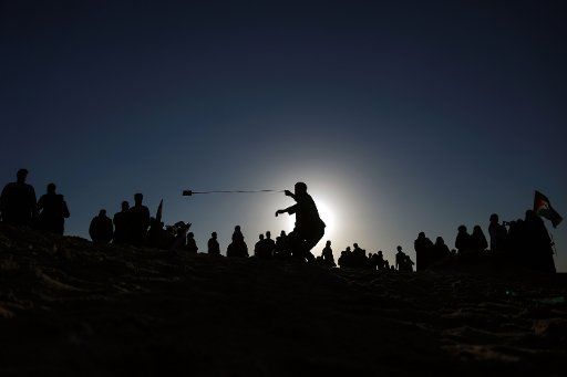 (181210) -- GAZA, Dec. 10, 2018 (Xinhua) -- A Palestinian protester uses a slingshot to hurl stones at Israeli troops on a beach near the border between Israel and the northern Gaza Strip, Dec. 10, 2018. At least 32 Palestinian protesters were injured on Monday during clashes with Israeli soldiers stationed on the border between the northern Gaza Strip and Israel, medics said. (Xinhua\/Stringer)