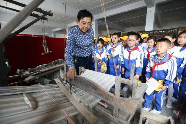 (190505) -- QINGDAO, May 5, 2019 (Xinhua) -- Sun Xianyong demonstrates a traditional-styled loom for primary school pupils at an idle factory in Henanya Village in Jimo District of Qingdao, east China\