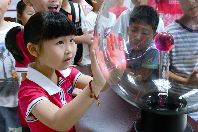(190722) -- CIXI(ZHEJIANG), July 22, 2019 (Xinhua) -- A pupil tries a plasma magic ball under the instruction of volunteers in Cixi City, east China\