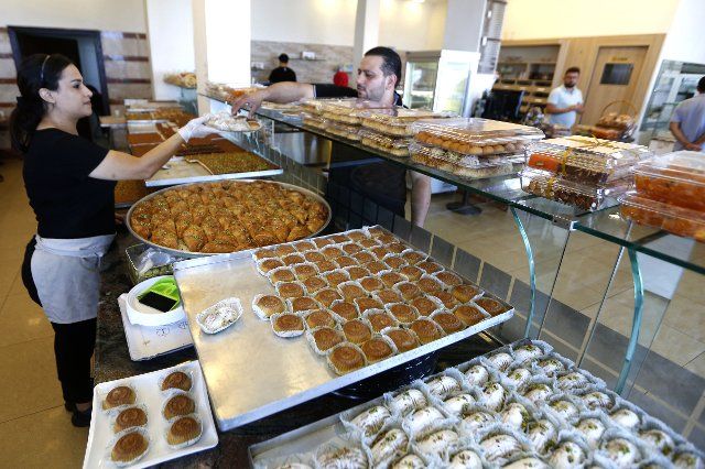 (190826) -- BEIRUT, Aug. 26, 2019 (Xinhua) -- A customer buys maamoul cakes at a pastry store in Saida, Lebanon, Aug. 25, 2019. The maamoul cake, a traditional food of Lebanon, is a kind of sweet made from semolina, butter, sugar and nectar water, and stuffed with walnuts, dates or pistachios. (Photo by Bilal Jawich\/Xinhua)