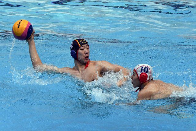 (191213) -- KUWAIT CITY, Dec. 13, 2019 (Xinhua) -- He Xingmeng (L) of China passes the ball during the preliminary match between China and Japan at the FINA World Men\