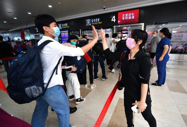 (200214) -- HAIKOU, Feb. 14, 2020 (Xinhua) -- A medical team member (L) goes to high fives with his colleague before leaving for Hubei Province at the Haikou Meilan International Airport in Haikou, south China\