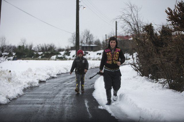 (200214) -- TEHRAN, Feb. 14, 2020 (Xinhua) -- Two boys walk on a road at a village in Gilan province, northern Iran, on Feb. 14, 2020. At least seven people died due to heavy snowfall and an avalanche incident in Iran\