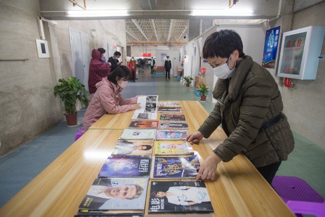 (200225) -- WUHAN, Feb. 25, 2020 (Xinhua) -- Staff members arrange magazines on display at the reading corner of a temporary hospital in Wuhan, central China\