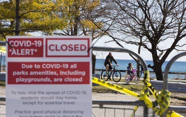 (200402) -- TORONTO, April 2, 2020 (Xinhua) -- People ride bikes near a closed park in Toronto, Canada, on April 2, 2020. The number of reported cases of COVID-19 in Canada hit 10,132, with the death toll rising to 127, as of Thursday morning, according to CTV. (Photo by Zou Zheng\/Xinhua)
