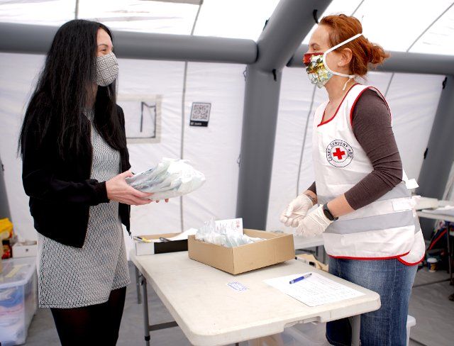 (200421) -- PRAGUE, April 21, 2020 (Xinhua) -- A Red Cross worker(R) passes face masks to a volunteer, who will deliver them to seniors in need, in Prague, the Czech Republic, April 20, 2020. (Photo by Dana Kesnerova\/Xinhua