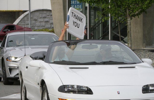 (200510) -- SURREY, May 10, 2020 (Xinhua) -- A participant holds a sign to express appreciation for frontline health workers during a parade near Surrey Memorial Hospital in Surrey, Canada, May 9, 2020. More than 100 Canadian car enthusiasts participated in parade, also a fundraiser, by driving their cars around the communities and hospitals in Surrey to show support for frontline health workers in the fight against COVID-19. (Photo by Liang Sen\/Xinhua)