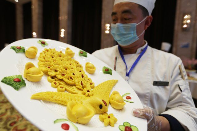 (201212) -- LINYI, Dec. 12, 2020 (Xinhua) -- A chef presents his work during a cooking competition in Yinan county of Linyi City, east China\