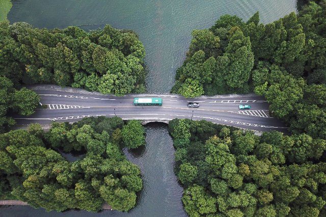 (201212) -- BEIJING, Dec. 12, 2020 (Xinhua) -- Aerial photo taken on July 30, 2018 shows an electric bus running on the Yanggongdi Causeway in the West Lake scenic area in Hangzhou, capital of east China\