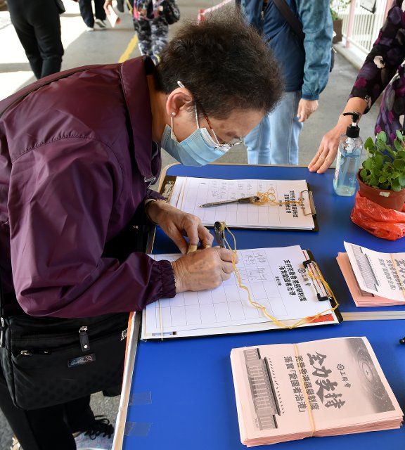 (210312) -- HONG KONG, March 12, 2021 (Xinhua) -- A citizen signs her name during a campaign in support of the decision on improving the electoral system of the Hong Kong Special Administrative Region by the National People\