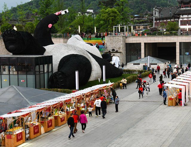(210408) -- CHENGDU, April 8, 2021 (Xinhua) -- Tourists visit a creative market next to the "Selfie Panda" sculpture at Yangtianwo square in Dujiangyan, southwest China\