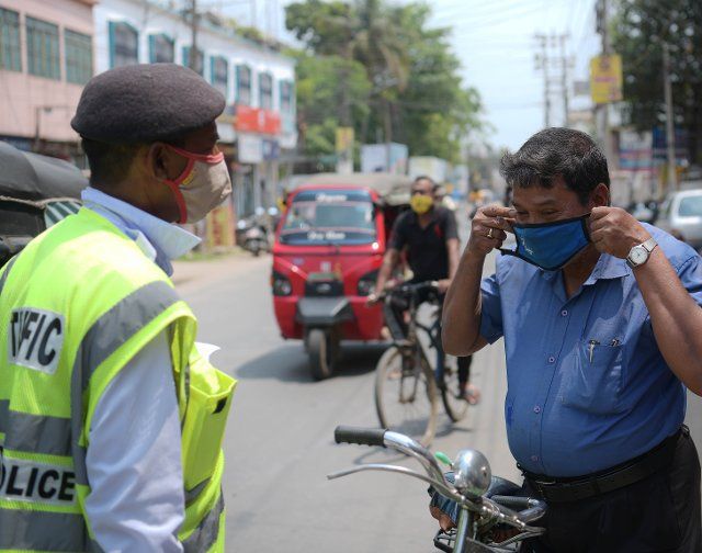 (210409) -- AGARTALA, April 9, 2021 (Xinhua) -- A police officer takes penalties from a man who is not wearing face mask amid the resurgence of COVID-19 cases in Agartala, the capital city of India\