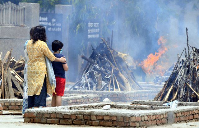 (210512) -- NEW DELHI, May 12, 2021 (Xinhua) -- Family members look at the funeral pyres for a COVID-19 victim at Sarai Kale Khan crematorium in New Delhi, India, May 12, 2021. (Photo by Partha Sarkar\/Xinhua