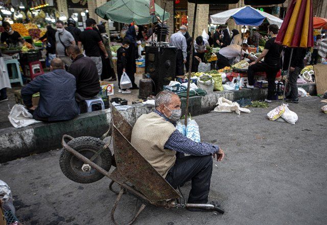 (210512) -- TEHRAN, May 12, 2021 (Xinhua) -- A worker rests in a wheelbarrow as people shop at a bazaar ahead of the upcoming Eid al-Fitr in Tehran, Iran, on May 12, 2021. Eid al-Fitr marks the end of the Islamic holy month of Ramadan. (Photo by Ahmad Halabisaz\/Xinhua